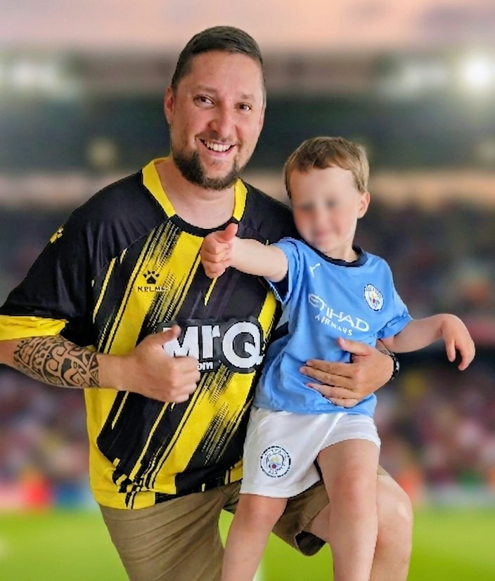 Un homme et un enfant en maillots de football posant avec un pouce levé.