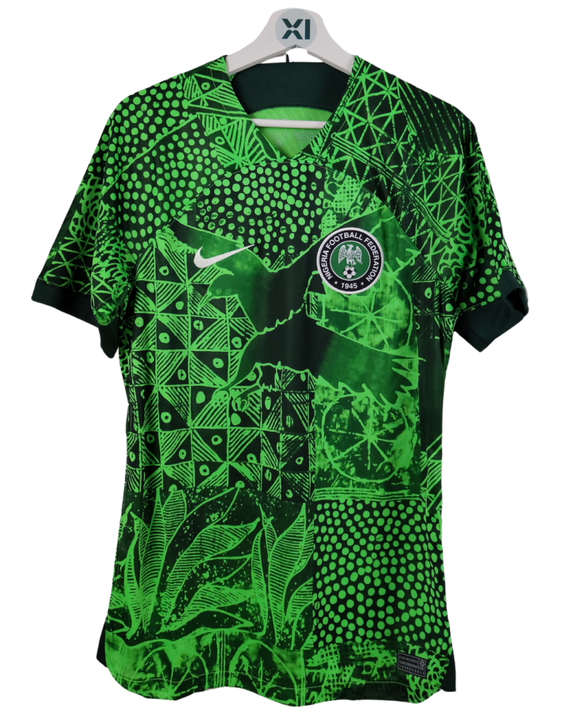Maillot de football domicile de l'équipe du Nigeria (saison 2022-2023), de couleur verte et noire avec un motif graphique complexe, incluant le logo Nike et l'écusson de la Fédération Nigériane de Football sur la poitrine.